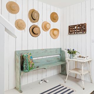 Entrance hall with white panelled walls, hats and turquoise painted bench