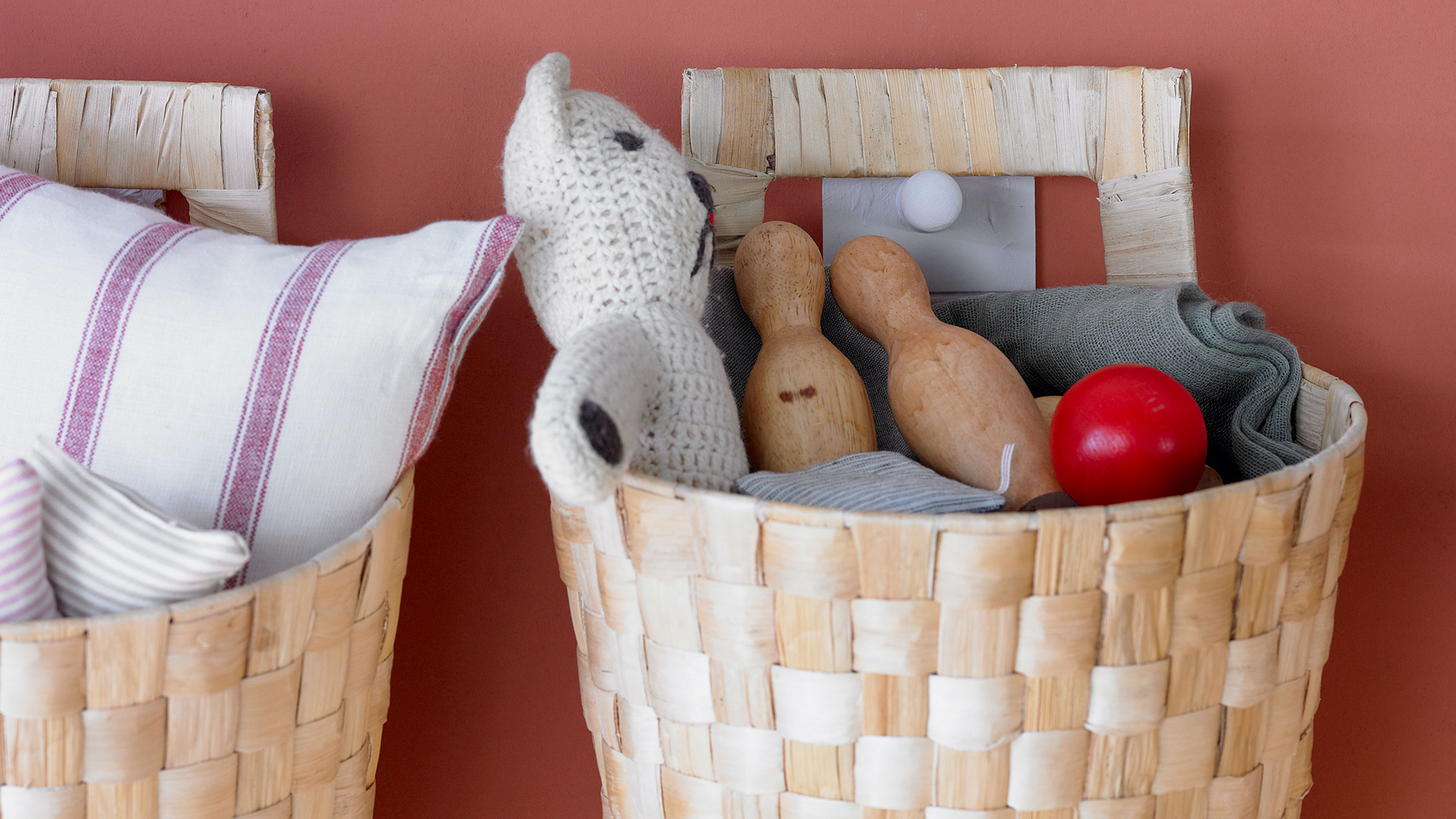 Pink wall with wall-mounted woven storage baskets for toys and soft furnishings