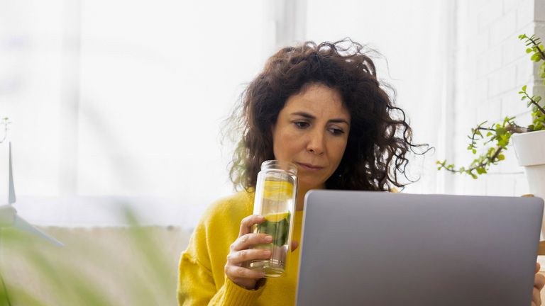Woman drinking water at laptop