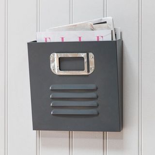 A steel magazine rack affixed to a white panelled wall.