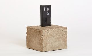 Artwork showing a stone block with a video cassette inserted in the top