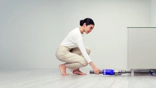Dyson Omni-glide review: picture of woman using vacuum to reach under sofa