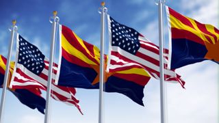 Flags of Arizona and United States waving in the wind on a clear day