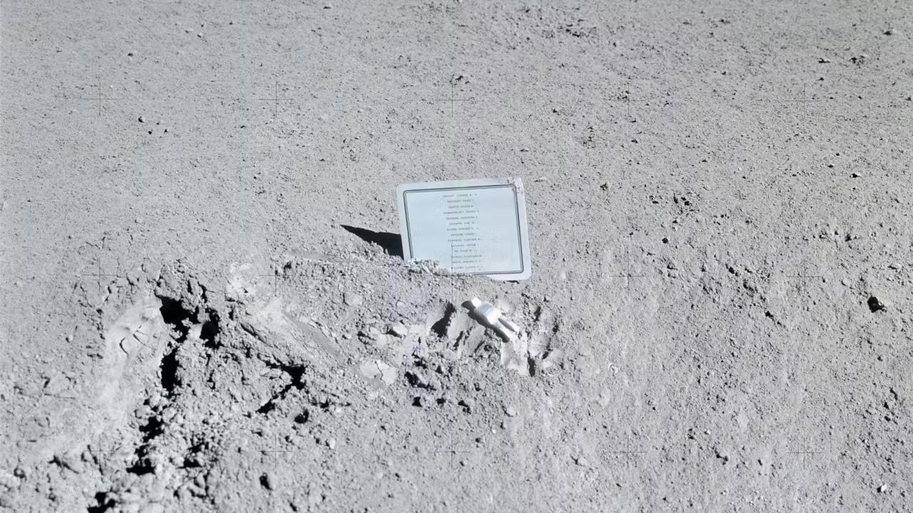 photo of a small silver plaque on the dusty gray surface of the moon