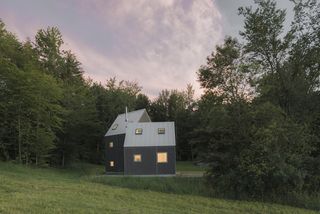 dusk view of timber clad Vermont cabin in the countryside