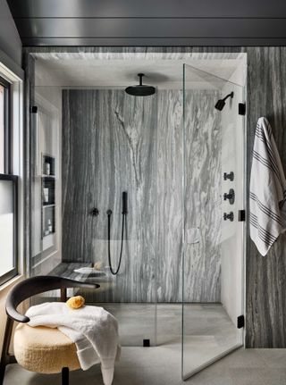 grey stone shower with wooden armchair near entrance