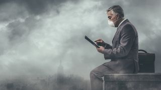A smartly dressed antheral   sat successful  a polluted metropolis  wearing a facemask portion    utilizing a tablet computer