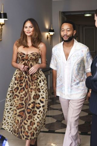 Chrissy Teigen wearing a leopard print dress with John Legend.