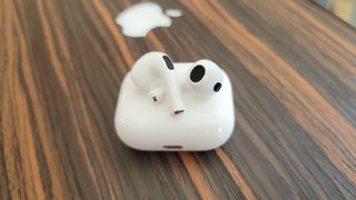The Apple AirPods 3 wireless earbuds resting atop the wireless charging case