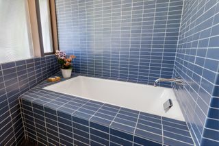 A built in bath surrounded by blue tiles