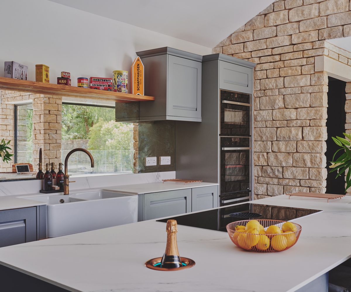 A Shaker-style kitchen with a large kitchen island and an exposed stone wall