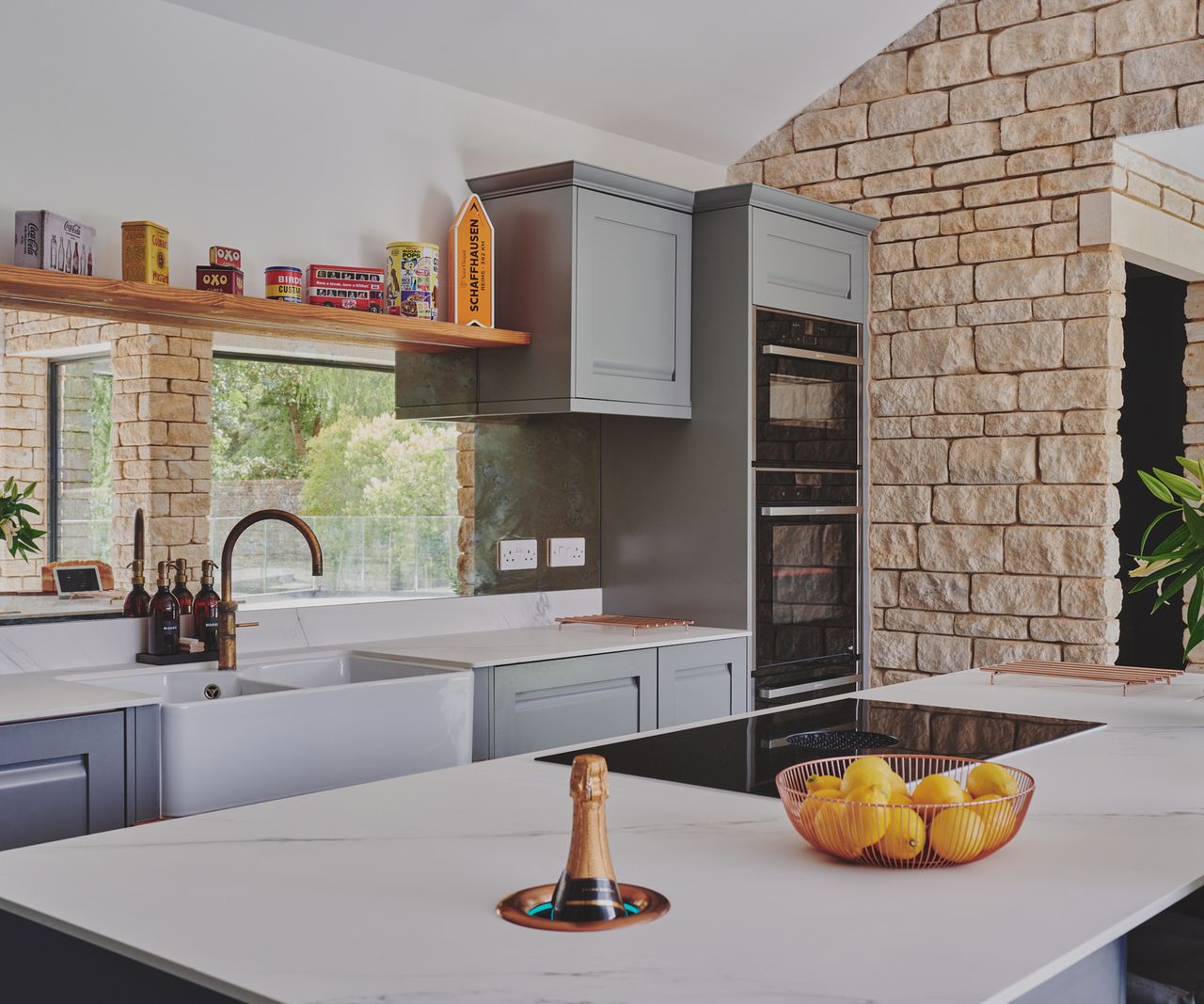 A Shaker-style kitchen with a large kitchen island and an exposed stone wall