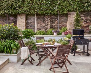 Walled courtyard patio with dining set and bbq with patio tile flooring