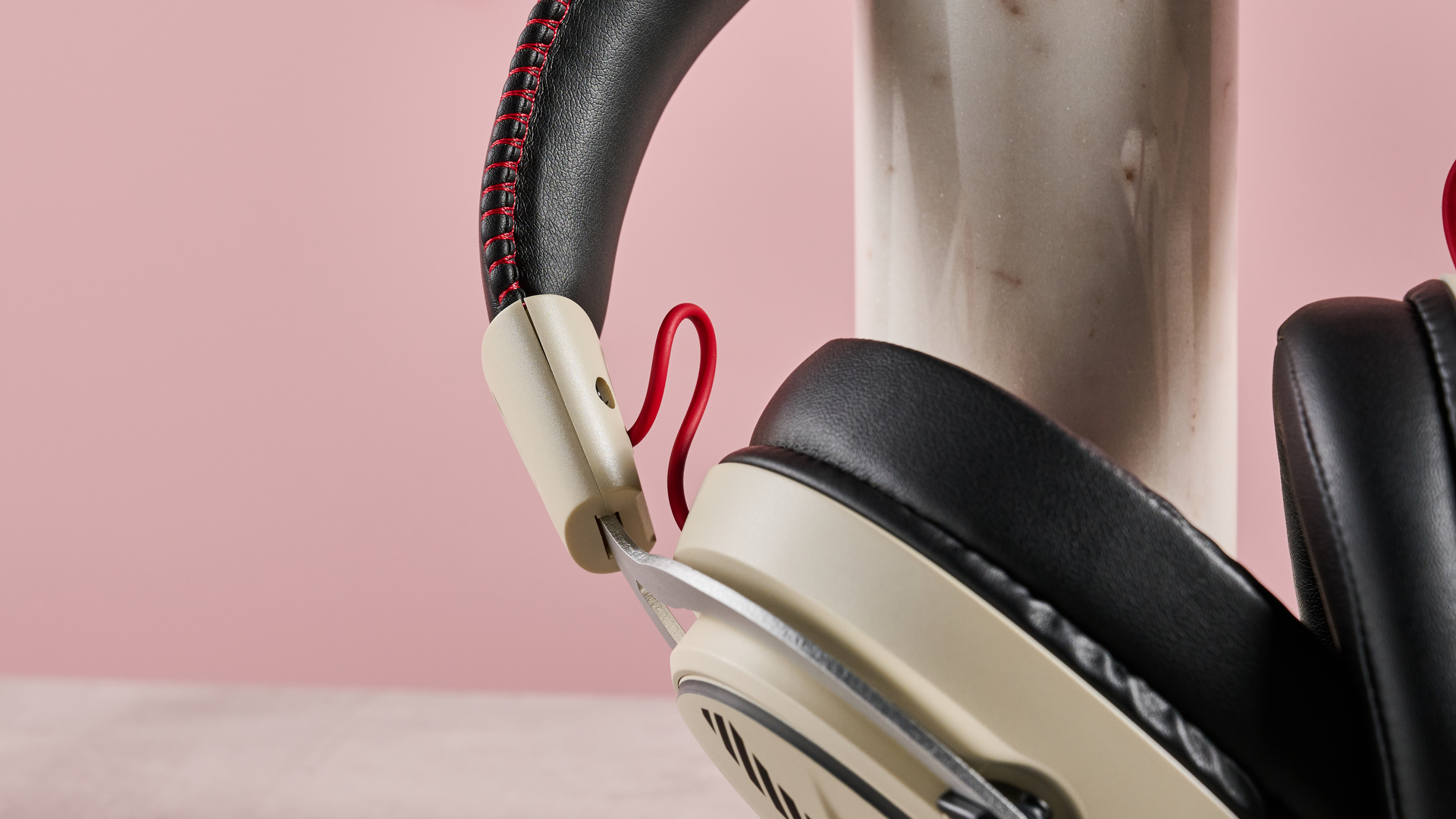Close-up of red wire on OXS Storm G2, leaning on plinth on desk with pink background
