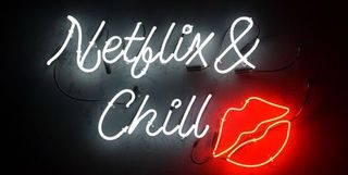 A neon sign reading "Netflix & Chill" in white with a pair of juicy lips in red.
