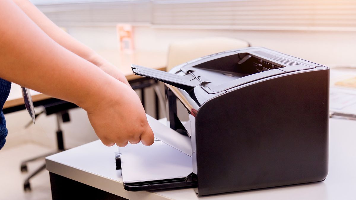 Person putting paper into a compact printer.