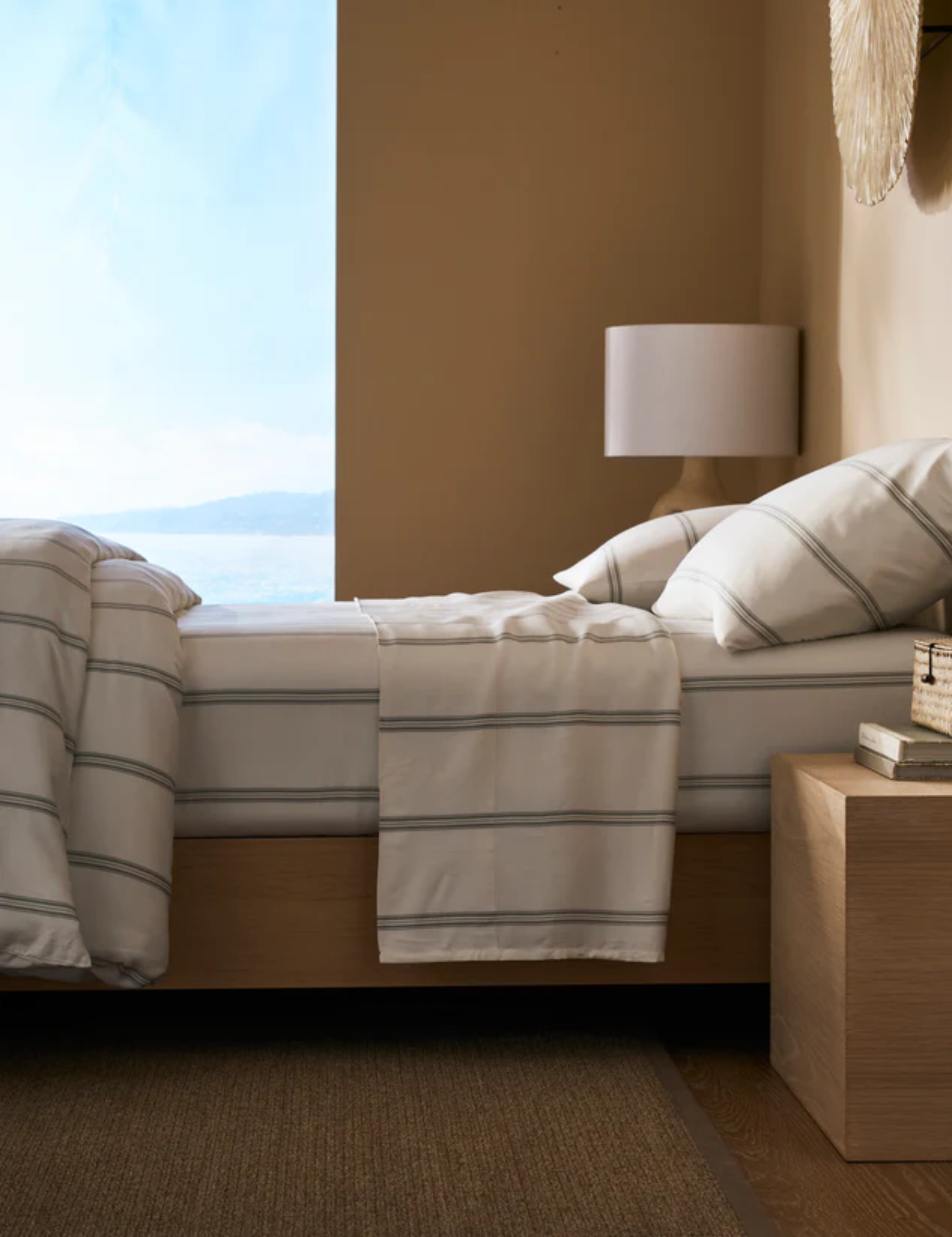 Neutral coastal bedroom featuring a sleek-lined modern bed frame and striped bedding