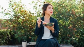 Image shows woman eating outside