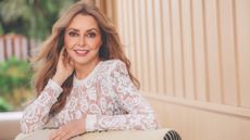 Carol Vorderman looking at the camera and smiling, wearing a white lace playsuit