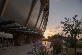 Exterior of the building captured from the bottom with flowers on the right photographed at dusk
