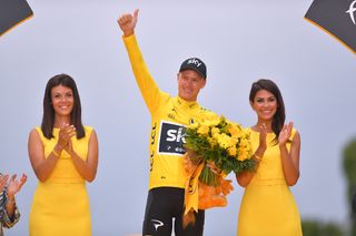 Podium hostesses stand on either side of Chris Froome on the final Tour de France podium