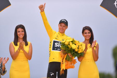 Podium hostesses stand on either side of Chris Froome on the final Tour de France podium