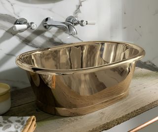 A metallic brass countertop basin in a small contemporary bathroom