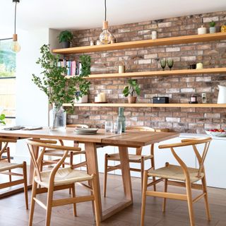 dining area with wishbone chairs, exposed brick wall with inset open shelving