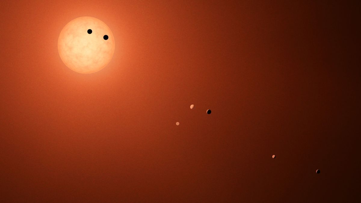 Artists illustration of the TRAPPIST-1 system, showcasing all seven planets in various phases. When a planet transits across the disk of the red dwarf host star, as two of the planets here are shown to do, it creates a dip in the star’s light that can be detected from Earth.