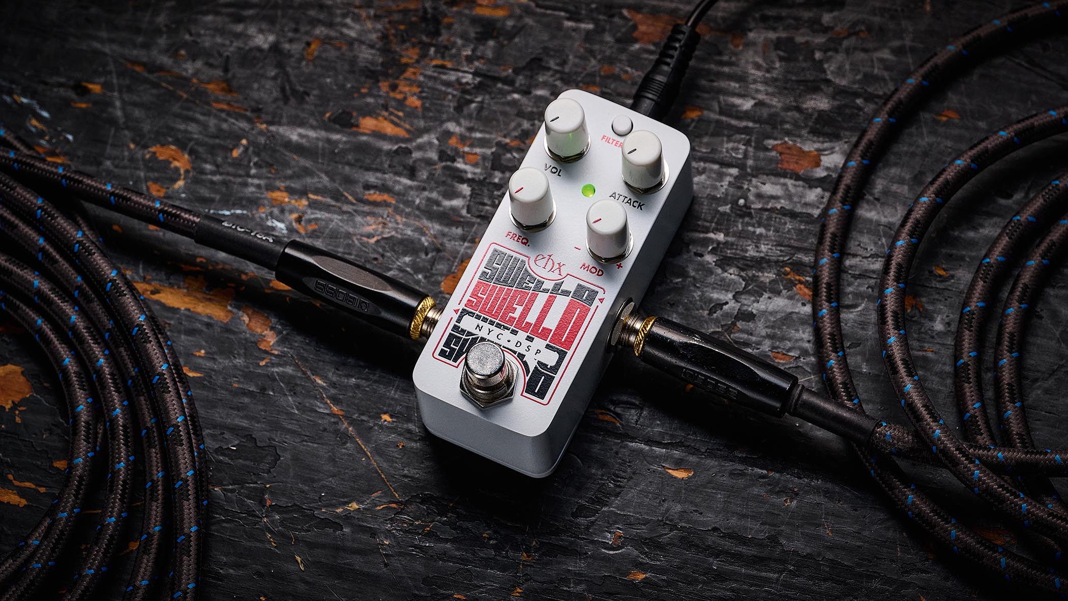 Electro-Harmonix Pico Swello: the compact mini-pedal is finished in white and has black and white text, four knobs, and is photographed against a distressed wood floor.