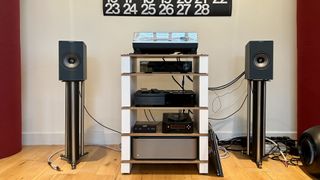 KEF Coda W active speakers, either side of an audio system and turntable, on top of a pair of speaker stands.