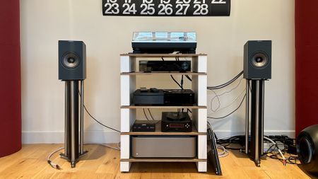 KEF Coda W active speakers, either side of an audio system and turntable, on top of a pair of speaker stands.