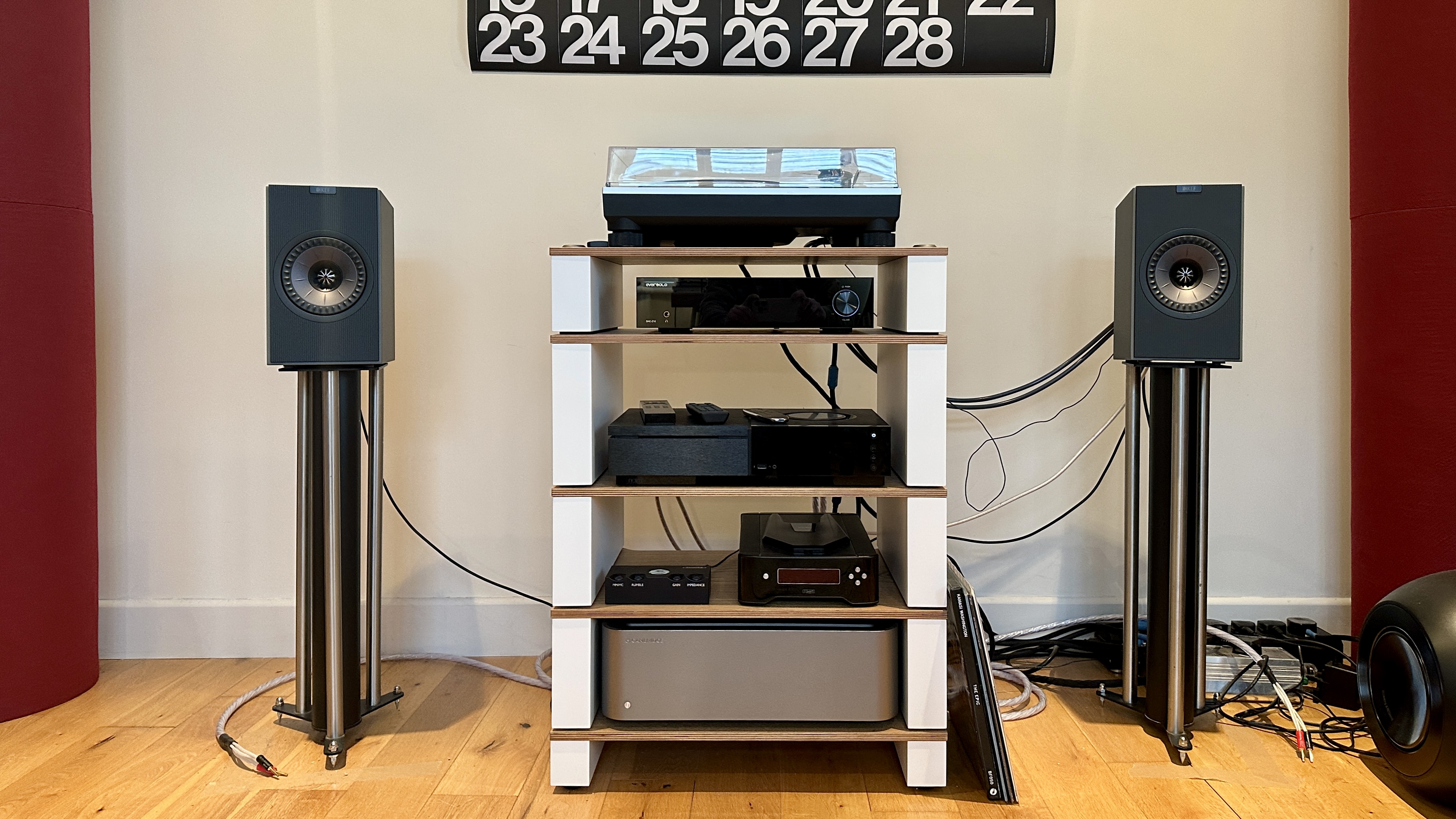 KEF Coda W active speakers, either side of an audio system and turntable, on top of a pair of speaker stands.