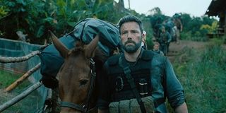 Triple Frontier Ben Affleck walking a donkey with bags of money in the jungle