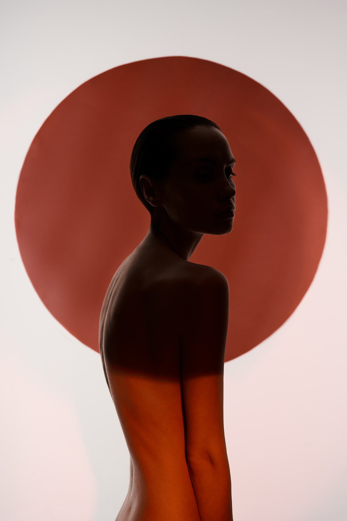 Woman standing in shadow in front of red and black circles