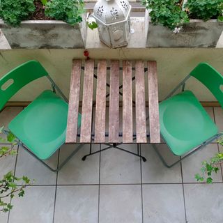 balcony garden with white flooring and green chairs