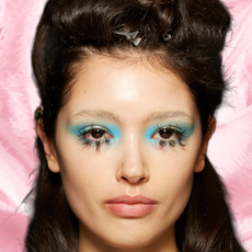 A woman with blue eyeshadow and long lashes staring into the camera.