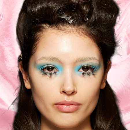 A woman with blue eyeshadow and long lashes staring into the camera.