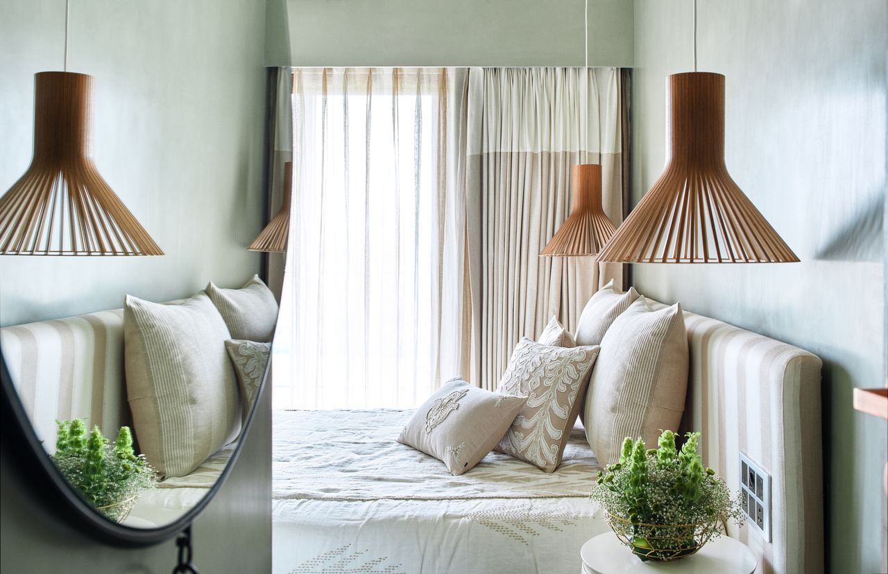 A bedroom in white with a mirror along the passageway