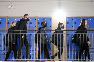 Secondary school children walking past row of blue lockers as schools go back in the UK