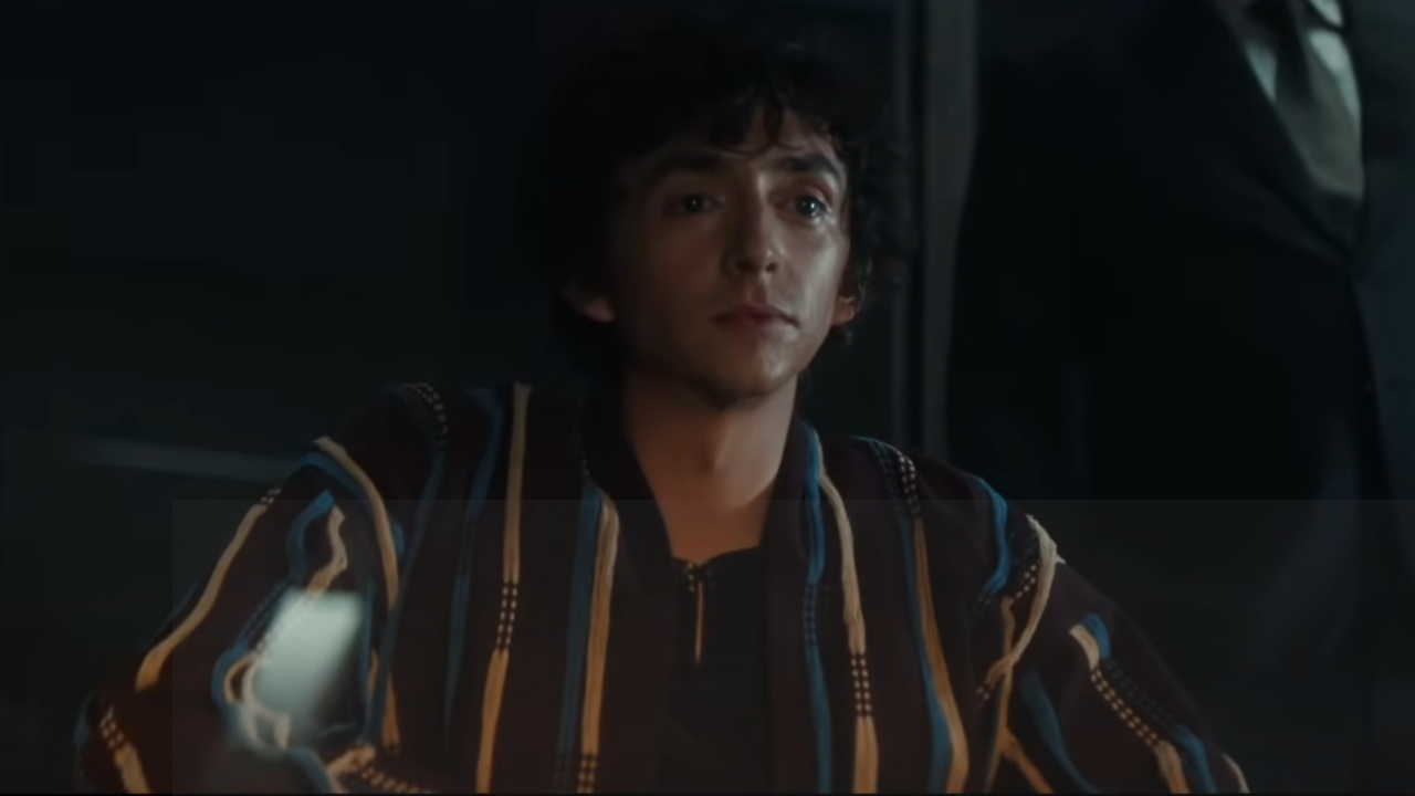Samuel Blenkin sits in a dim office with a look of cryptic interest in Alien: Earth.