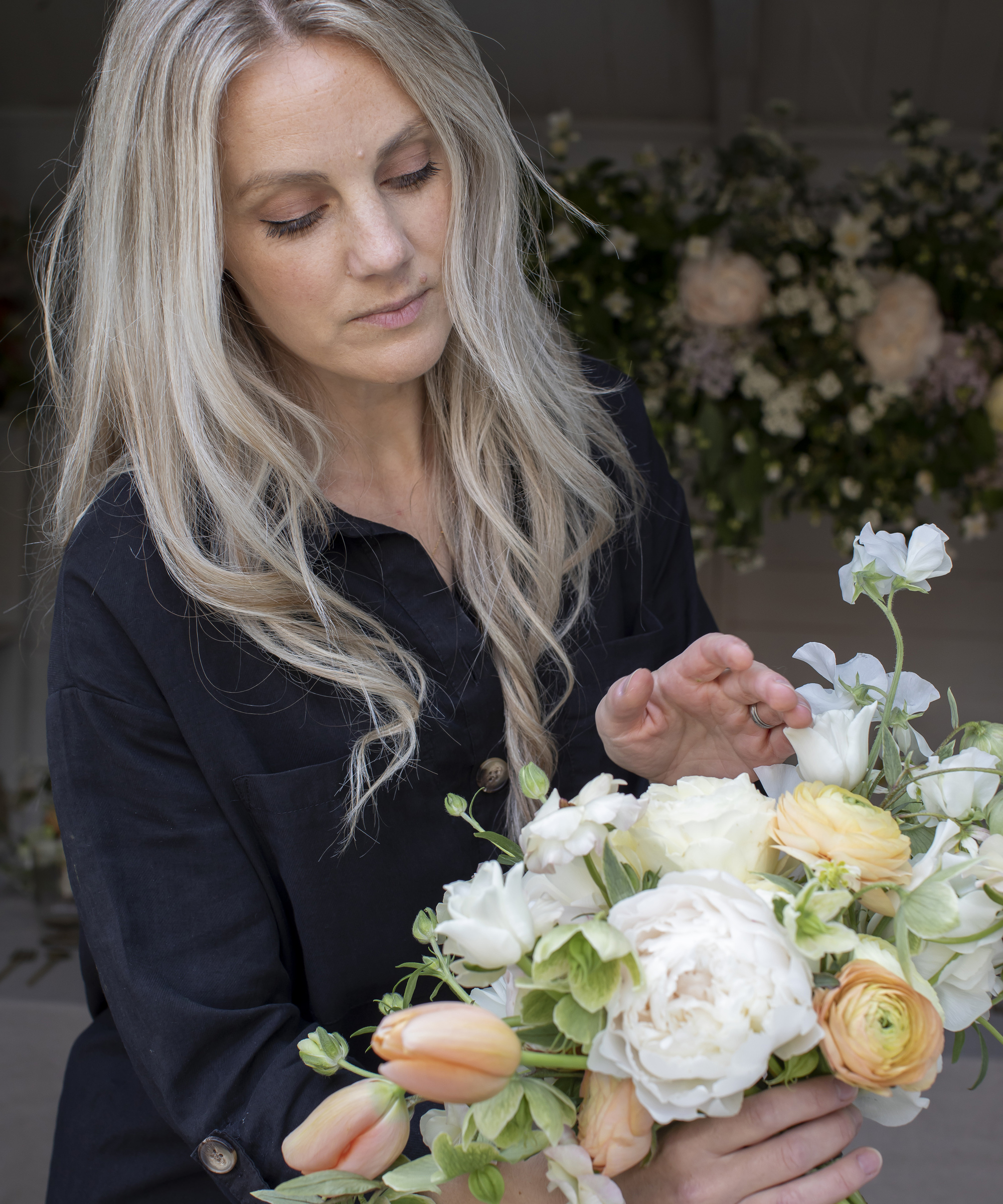 Woman with blonde hair holding a hand-tied bouquet with white, peach and lemon flowers