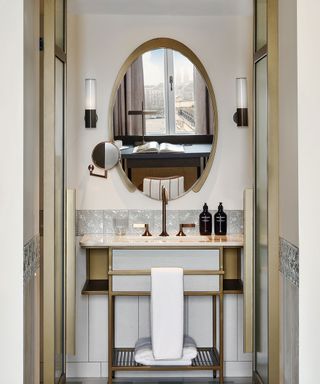 Bathroom basin with dark brass fixtures and oval mirror