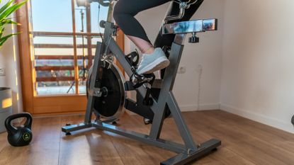 Woman using exercise bike and kettlebells at home