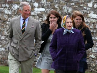 Princess Beatrice, King Charles, Princess Eugenie and Queen Elizabeth walking in front of a brick wall wearing coats and scarves