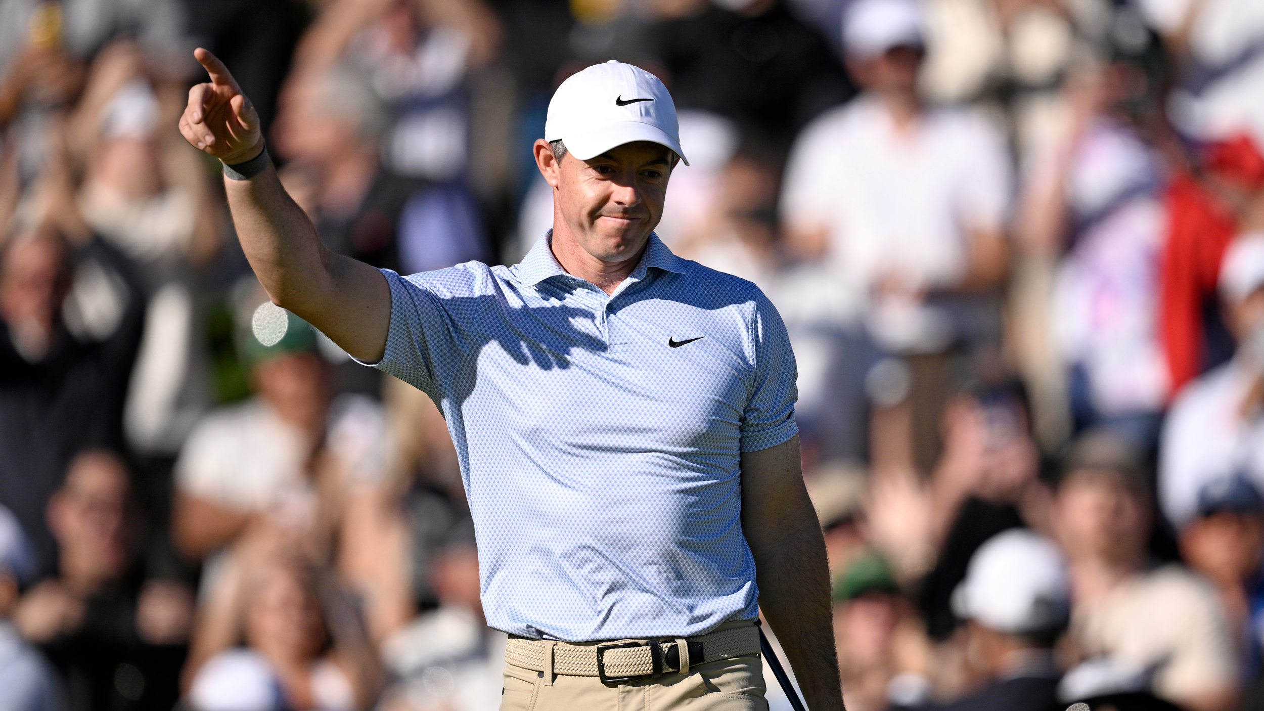Rory McIlroy wearing a sky blue polo celebrating a holed putt