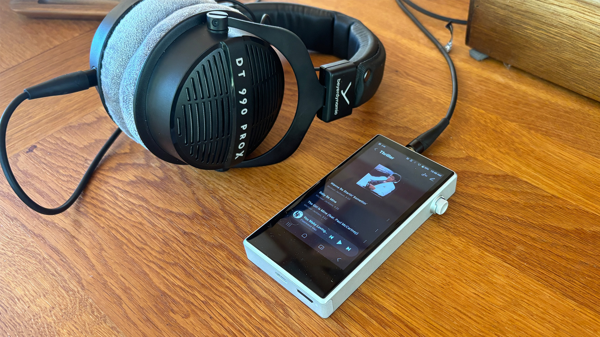 Astell &amp;amp; Kern PD5 portable music player on wooden table plugged into Beyerdynamic headphones, on display is Michael Jackson