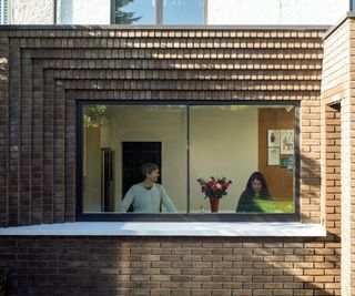 rear brick extension with corbelled brick detailing around large kitchen window with white serving shelf area outside