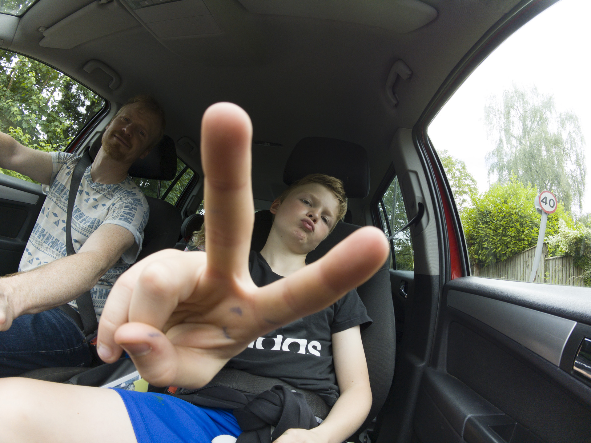 Boy doing peace sign in the passenger seat of a car, taken with the Insta360 Go 3S