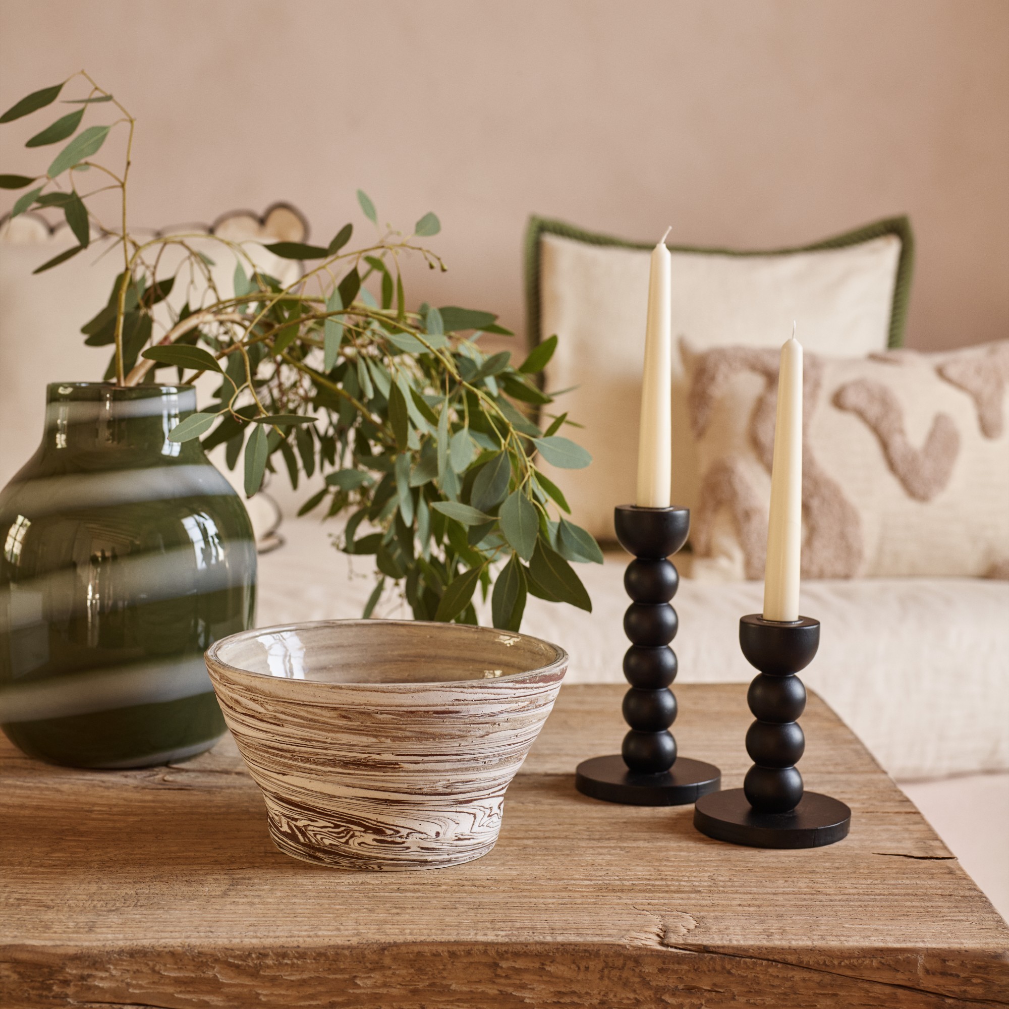 A coffee table in a living room decorated with pieces from George Home's Crafted Calm range like the marbled bowl, striped glass vase and black candle holders